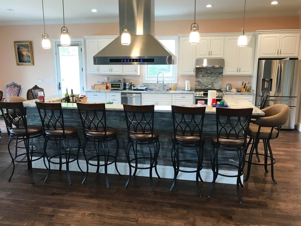 Modern kitchen with long island, seven barstools, white cabinets, Proline PLJI 102 stainless hood; ProlineRangeHoods.com.