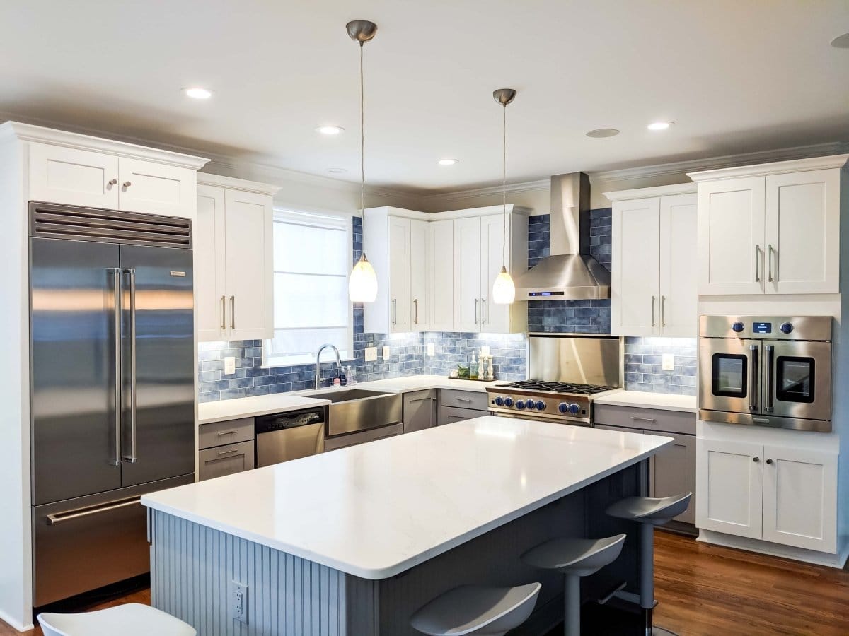 Modern kitchen with white cabinets, ProlineRangeHoods.com PLJW 130 wall-mounted hood, 900/1200 CFM, island, LCD controls.