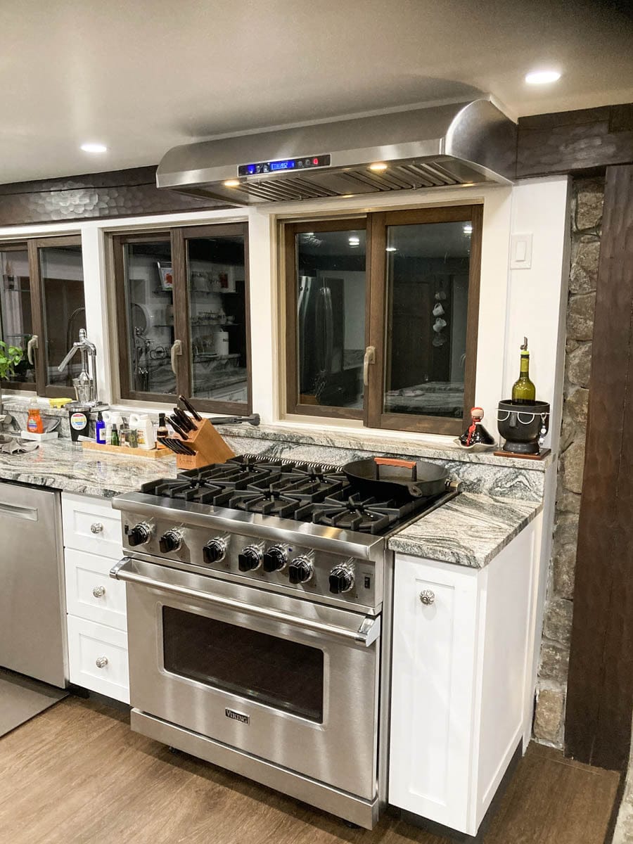 Modern kitchen with gas stove, marble counters, Proline PLJW 117 range hood (900 CFM) from ProlineRangeHoods.com.