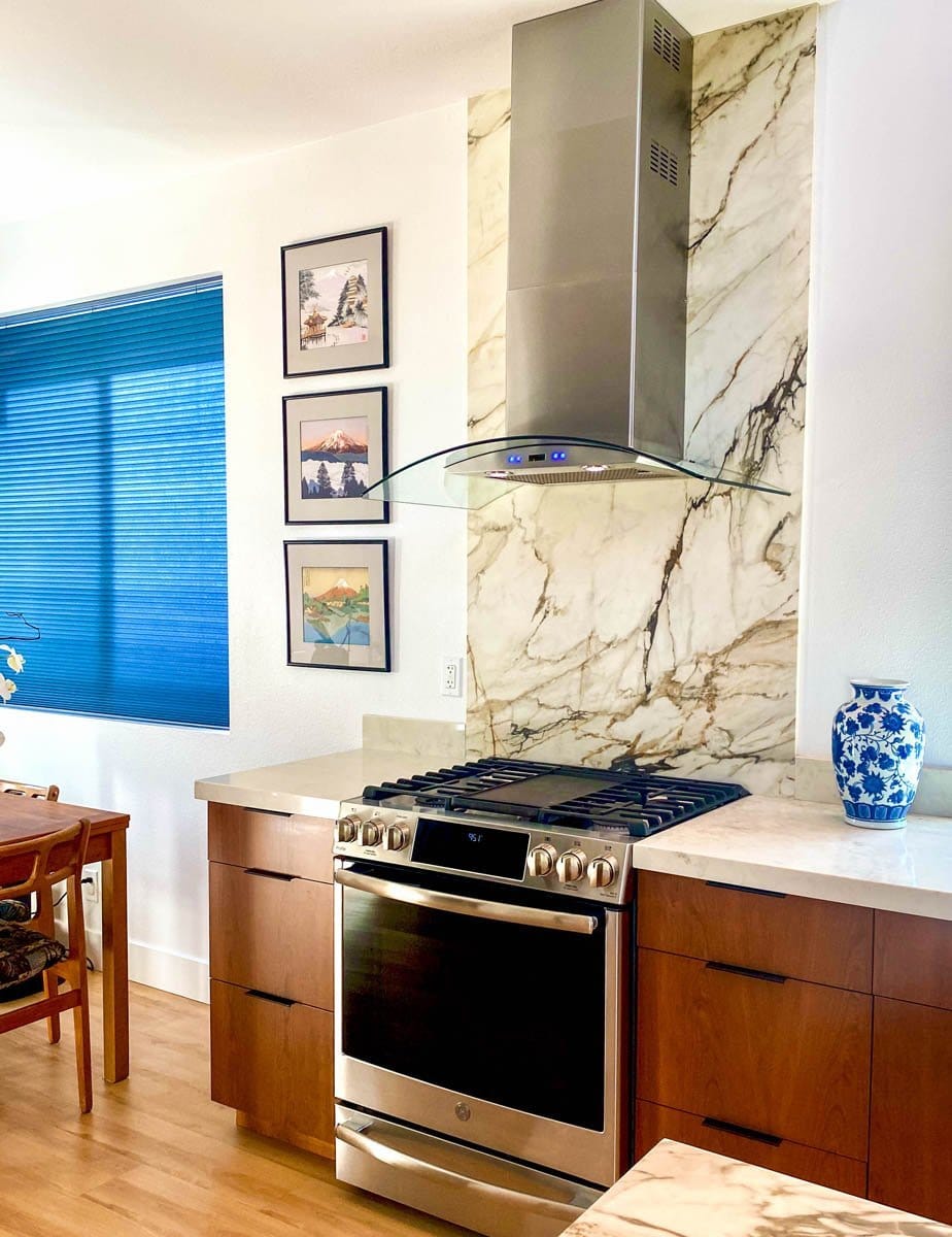 Modern kitchen with marble backsplash, Proline PLFW 544 range hood, stove, blue vase, framed art. ProlineRangeHoods.com.