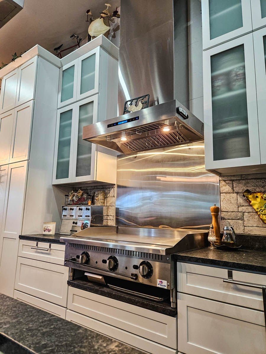 Sleek kitchen featuring ProlineRangeHoods.com PLFW 755 range hood with dual motor tech & 1100 CFM, paired with white cabinets.