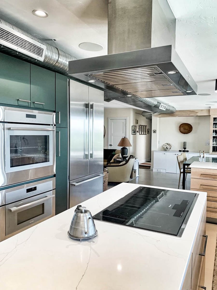 Modern kitchen: green cabinets, white countertop, induction stove, Proline PLFI 750 stainless hood. ProlineRangeHoods.com.