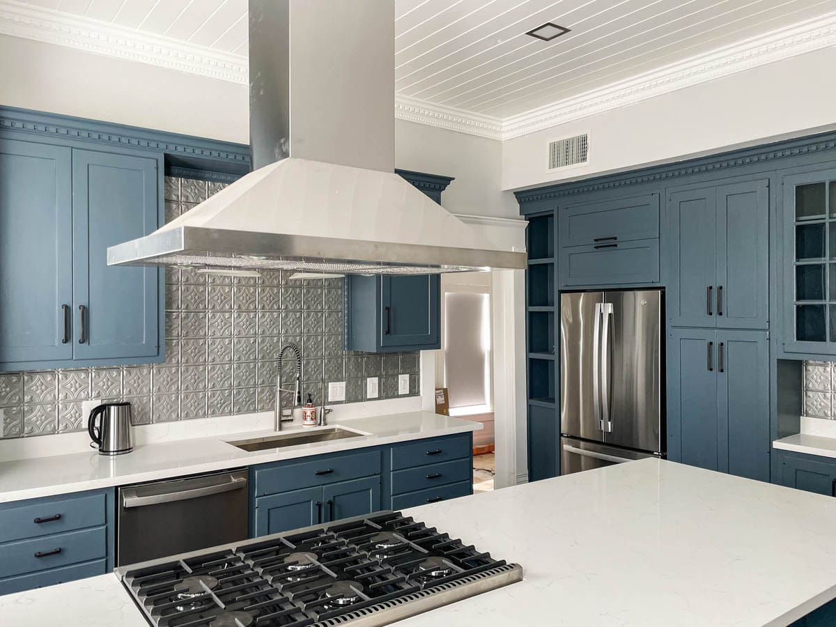 Modern kitchen with blue cabinets, stainless appliances, Proline PLFI 520 island hood from ProlineRangeHoods.com over stove.