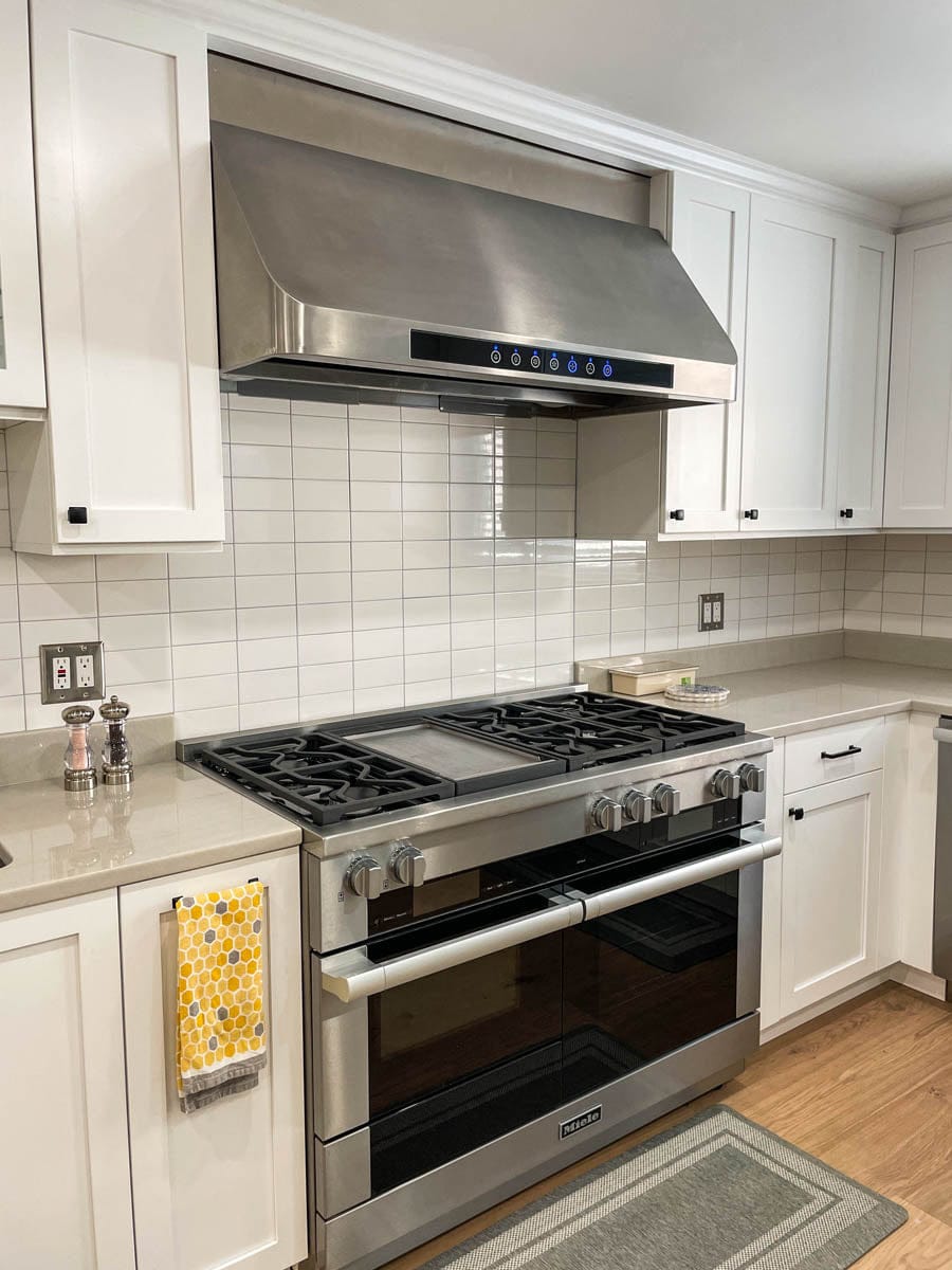Modern kitchen featuring ProlineRangeHoods.com PLJW 101 Under-Cabinet Range Hood, ducted with powerful CFM. White cabinets/tile.