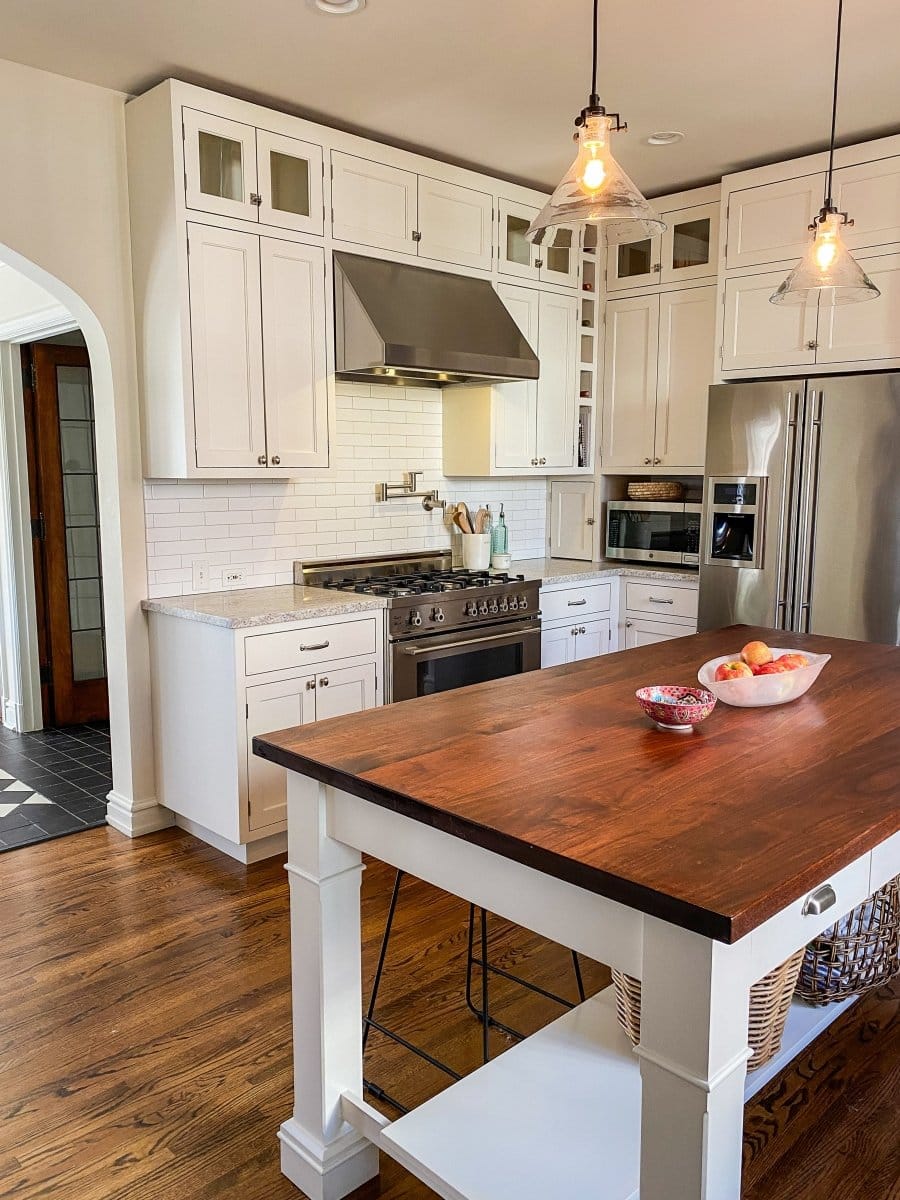 A modern kitchen with white cabinets and stainless appliances, including a Proline Range Hood from ProlineRangeHoods.com.