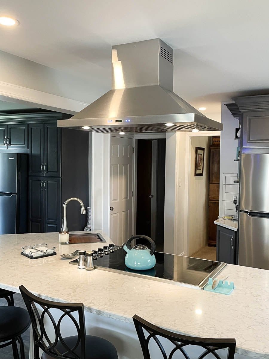 Modern kitchen with marble island, black chairs, stainless appliances, Proline PLFI 520 Hood. ProlineRangeHoods.com.
