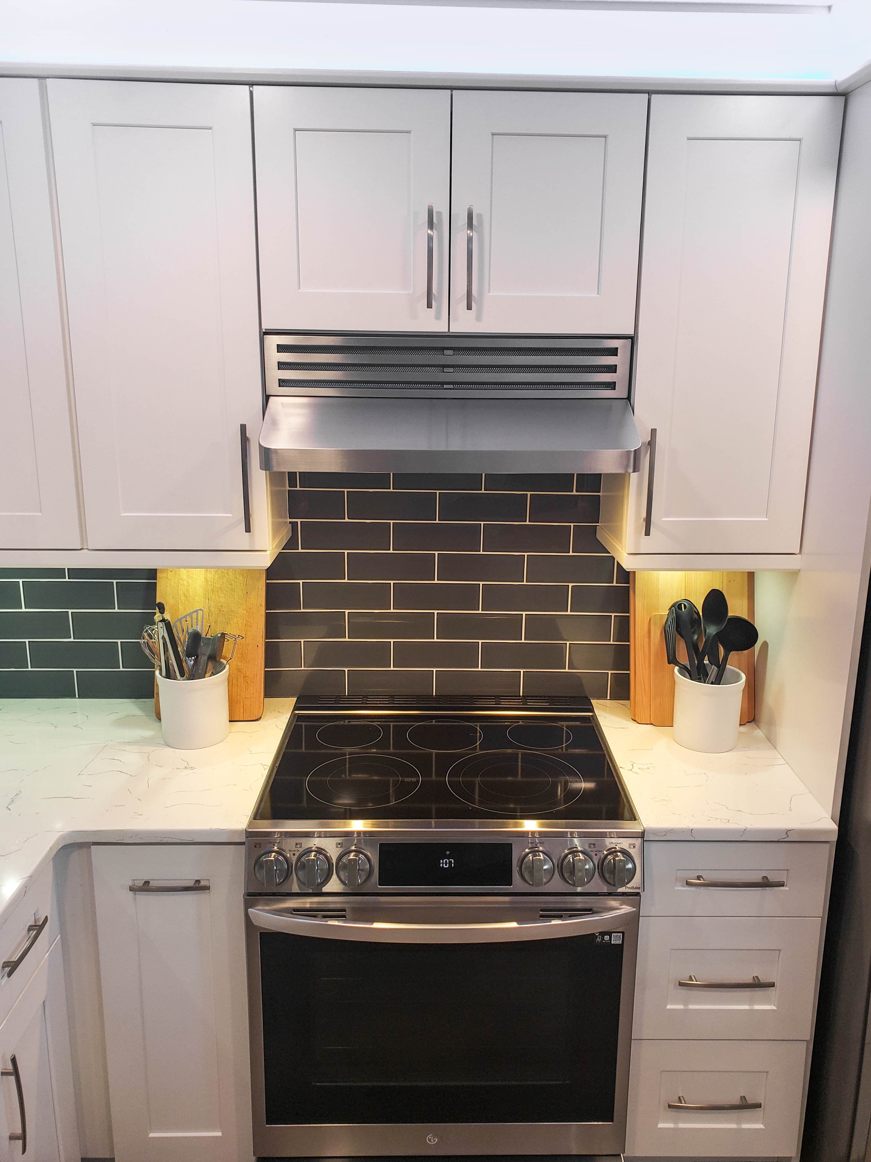 Check out ProlineRangeHoods.com for a modern kitchen with white cabinets, a Proline PLJW 185 range hood, and an electric stove.